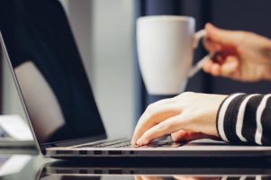 female-hands-typing-on-keyboard-of-laptop-while-holding-cup-of-coffee-working-at-home-concept_1356-207