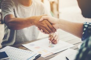 close-up-of-two-business-people-shaking-hands-while-sitting-at-the-working-place_1150-1817